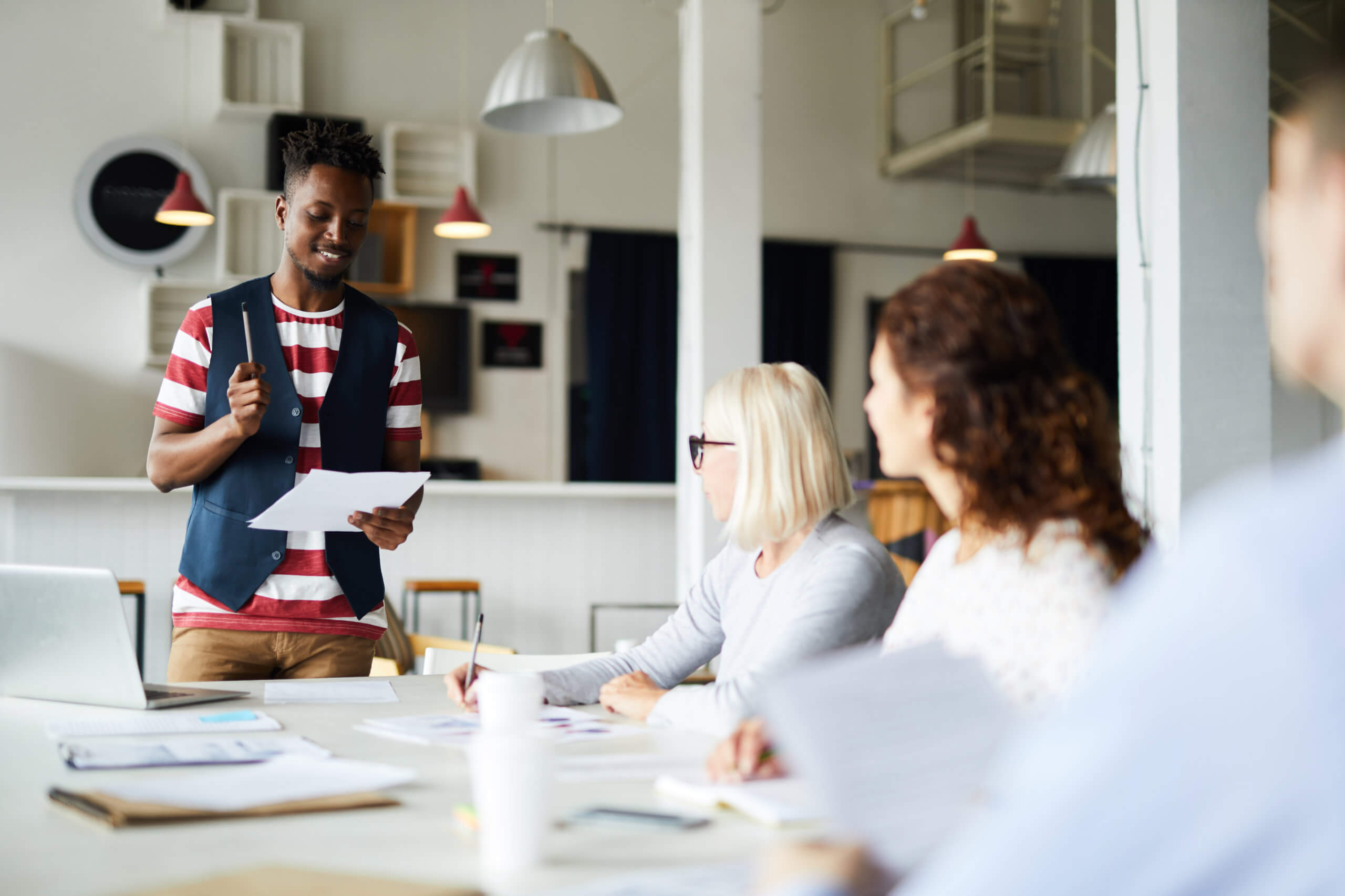 Young black employee presents to diverse work group in training session