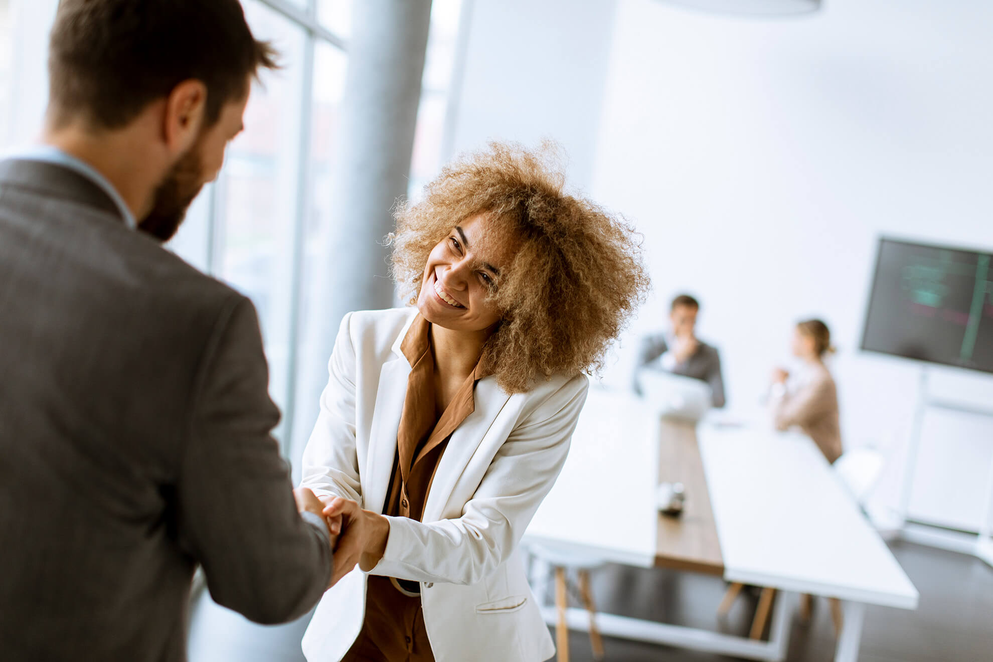 two business people shaking hands, smiling, and demonstrating ethical behavior in the workplace