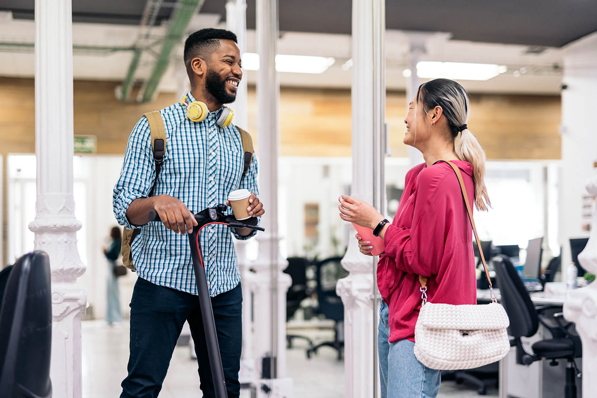 two multicultural coworkers in office smiling and discussing their employee compliance training sessopm