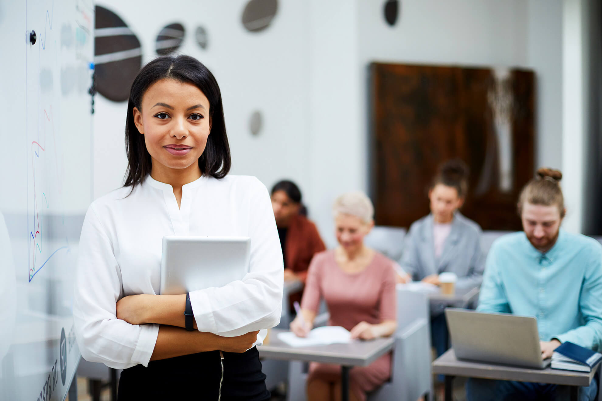 female presenter in corporate office conducting sexual harassment training to diverse employee team at desks