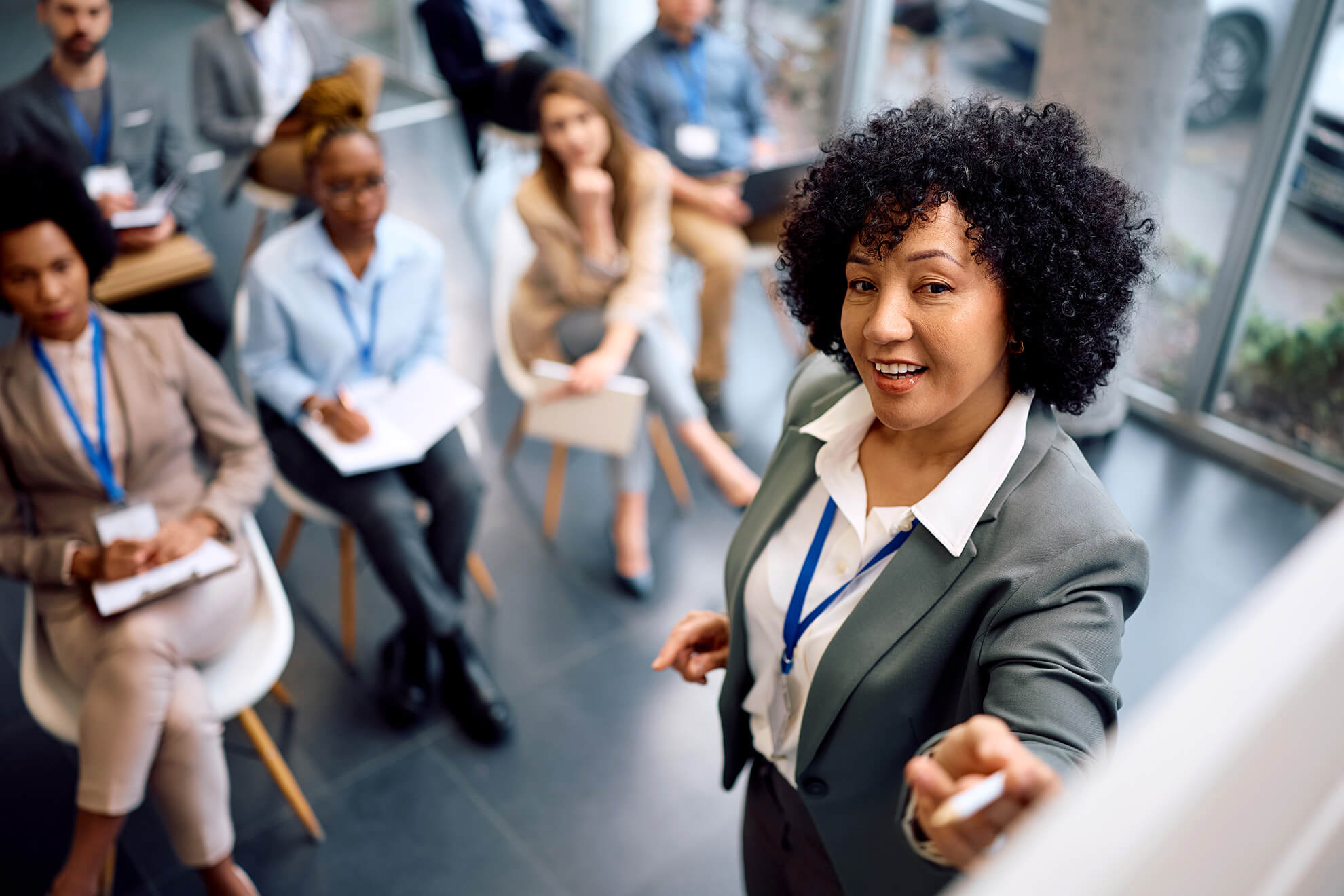 Female Trainer standing at whiteboard reviewing California Compliance Workplace Training Programs with corporate audience